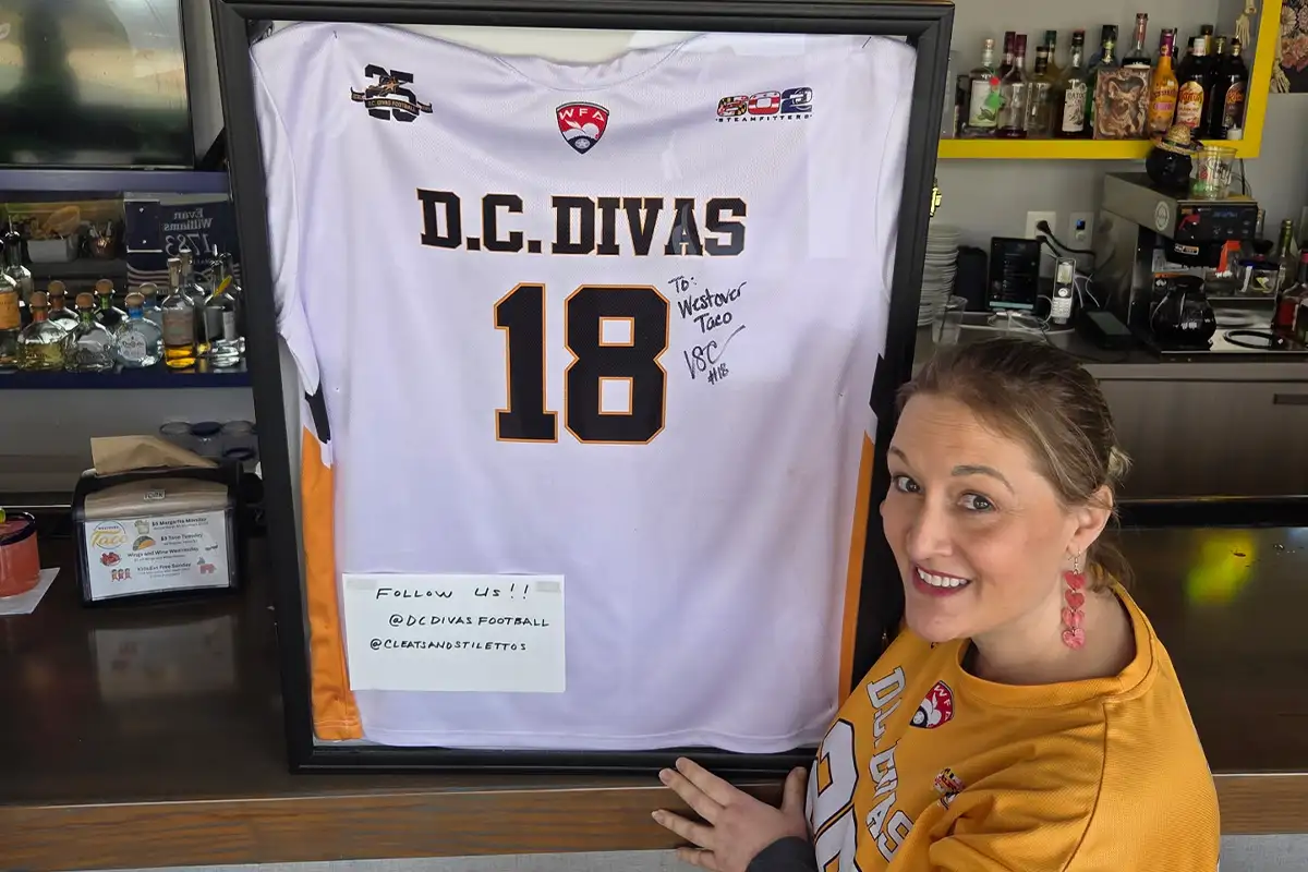 Sarah White poses beside a framed DC Divas jersey at Westover Taco