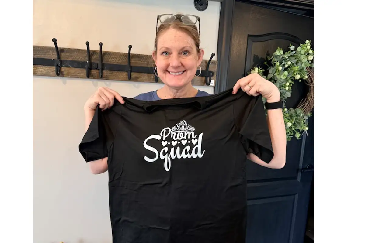 Kimberly Harris owner of A New View Home Decor holds up a Prom Squad T-Shirt