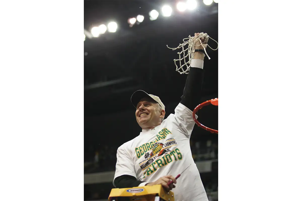 Jim Larrañaga holds net after beating UConn