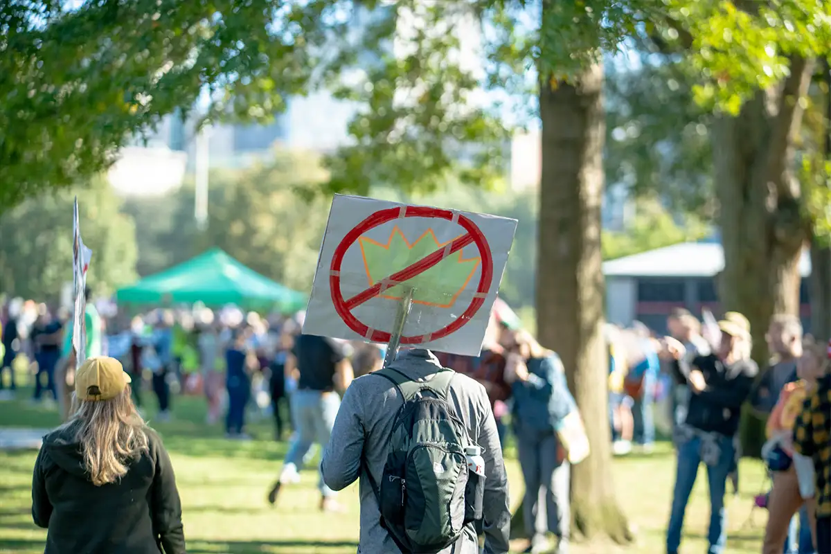 a man holds up a sign of a crown with a lawn drawn though it at a No Kings protest