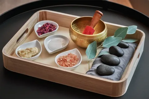 a bamboo tray with lotion, sea salt and other spa treatment items