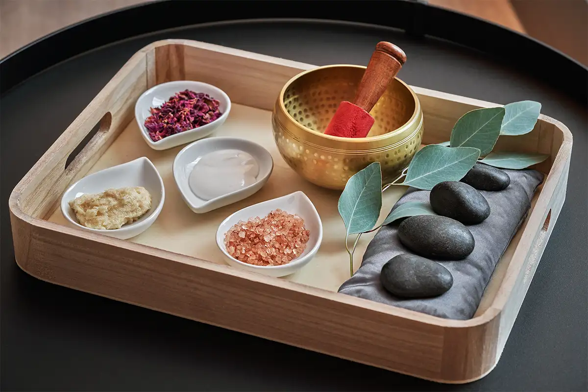 a bamboo tray with lotion, sea salt and other spa treatment items