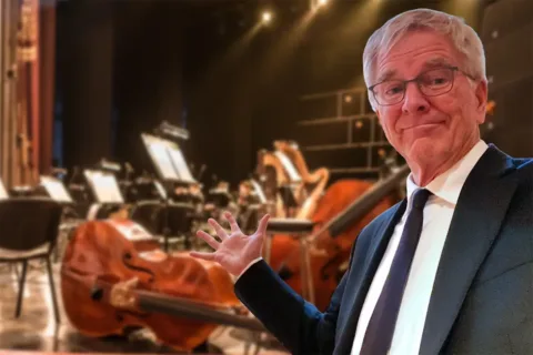 Rick Steves stands in front of an orchetra