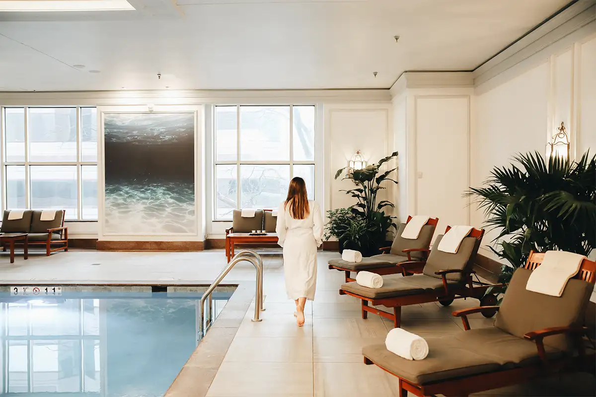 A woman in a robe walks past the pool at The Ritz-Carlton Spa Tyson’s Corner