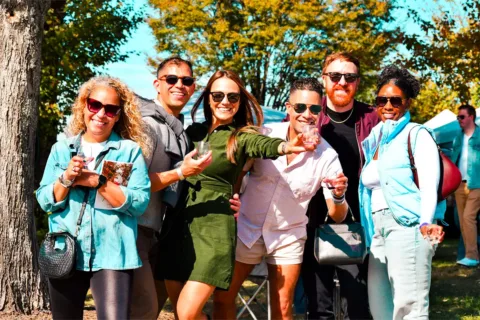 5 people outdoors holding wine glasses smiling at the camera