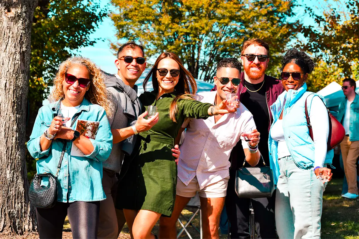 5 people outdoors holding wine glasses smiling at the camera