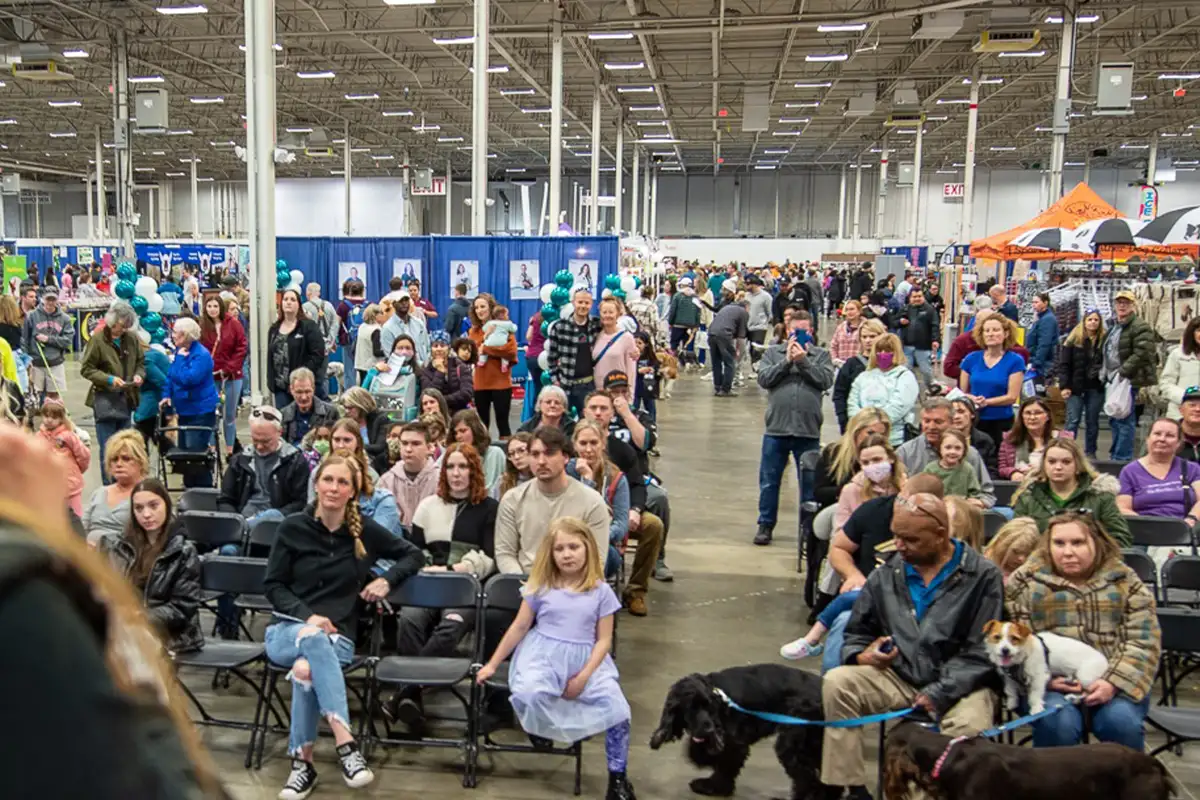 guests sit and listen to a speaker on stage at the Super Pet Expo