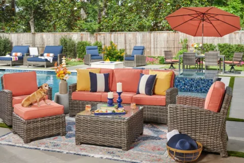 colorful outdoor furniture sits by a pool with a small dog on one of the chairs