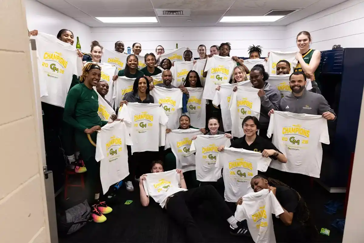 George Mason women's basketball team holding up championship t-shirts