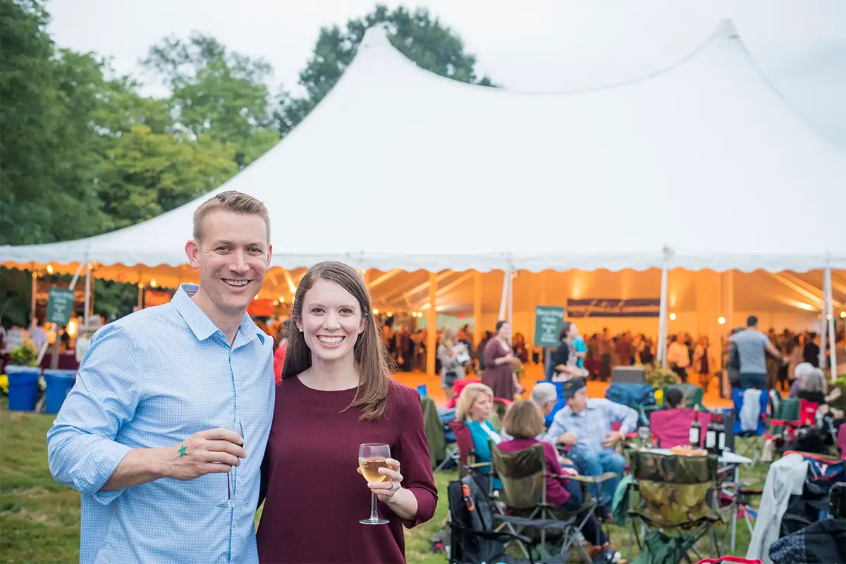 a couple holds wine glasses in front of tent on the lawn at Mount Vernon