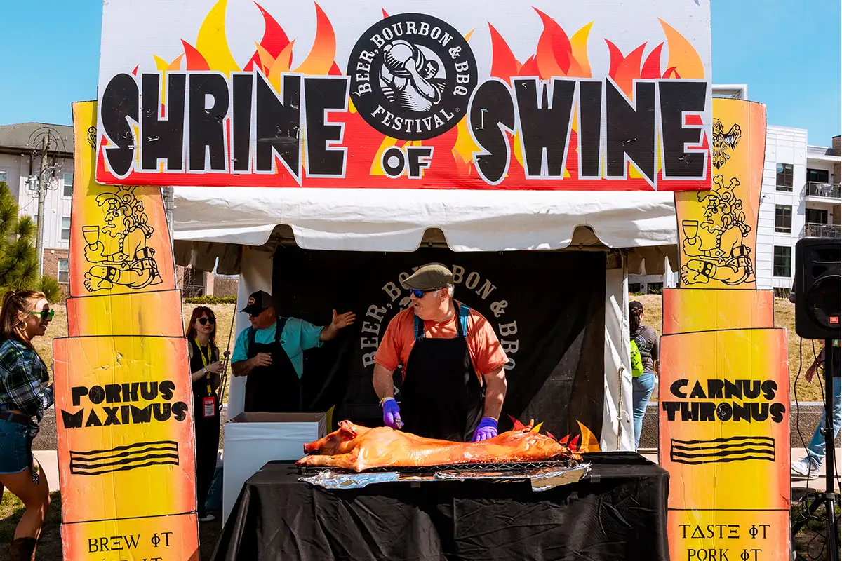 Man carving roasted pig at Beer, Bourbon & BBQ Festival
