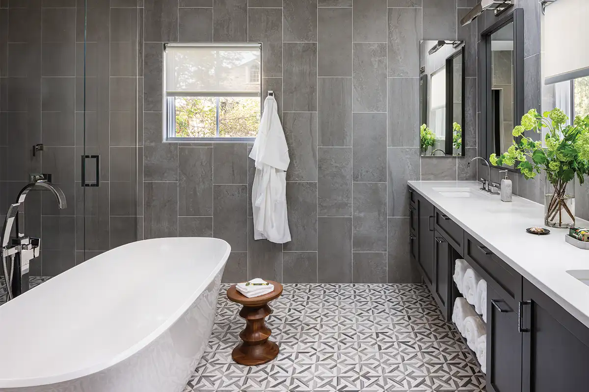 The bathtub is Amiata by Victoria & Albert and the concrete-look porcelain wall tiles are by Marble Systems. The flooring, also by Marble Systems, is Avenza Light, Snow White Multi Finish Marmara Marble Mosaic.
