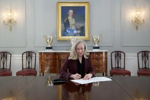 Governor Abigial Spanberger sits at a table in the Governors mansion signing bills into law.