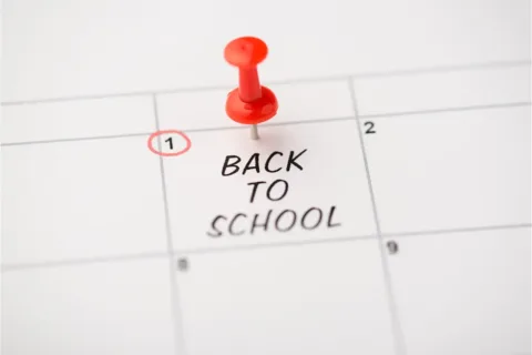 Closeup photo of mark on calendar at first inscription back to school with red pushpin