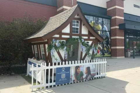 a playhouse that looks like a mini cottage sits on the sidewalk outside of Fair Oaks Mall in Fairfax