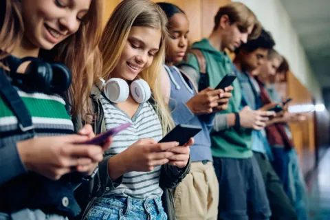 high school students lean against lockers looking at their cellphones