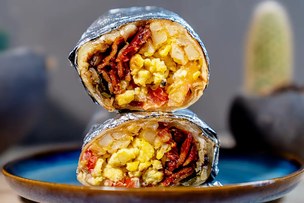 a burrito wrapped in foil on a plate at Monstera Burrito