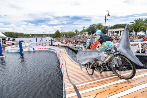 team riding tandem bike designed as shark over floating obstacle course