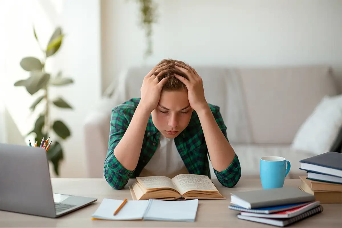 Student sitting at desk doing work and stressed