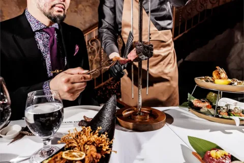 Chef cutting into skewered steak at Churasuko