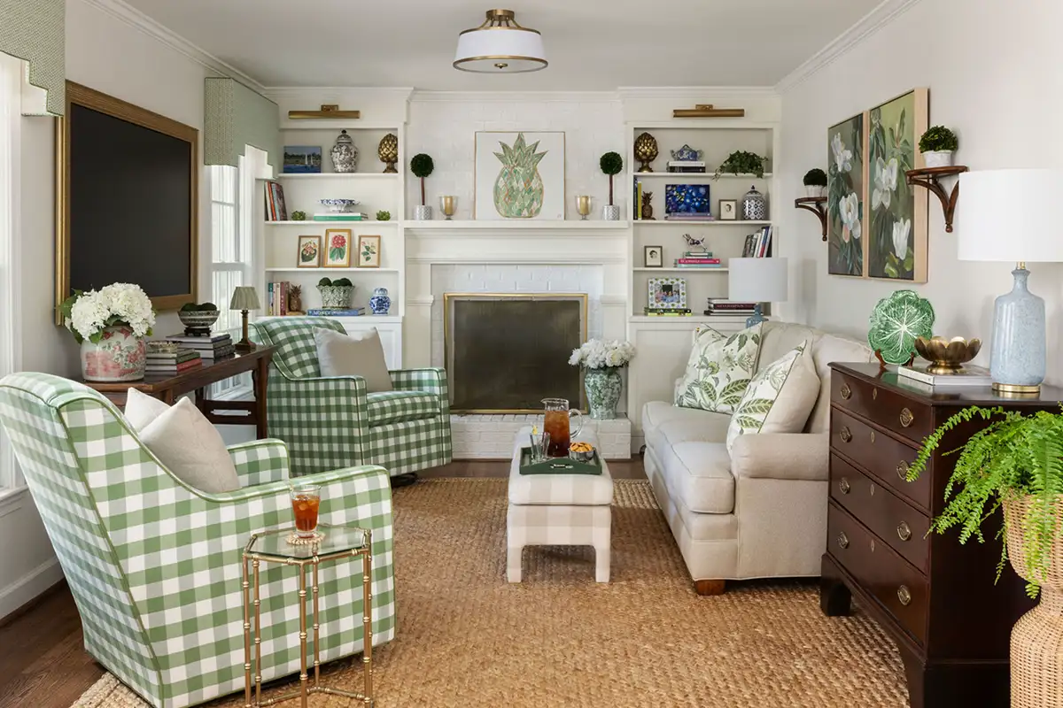 Family room interior with green accents, a fireplace, built-in bookshelves, and library sconces of the Merchant family home in Alexandria