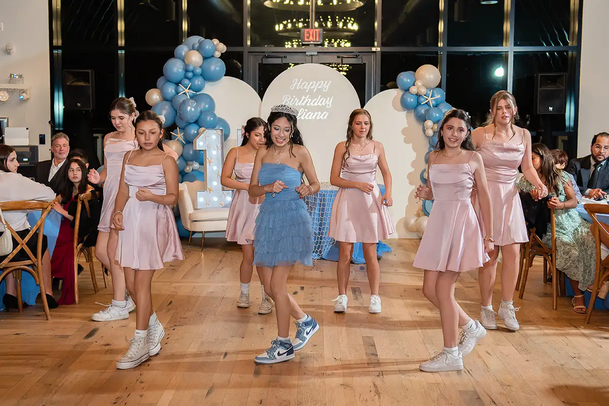 Girls in dresses and sneakers dancing at quinceañera
