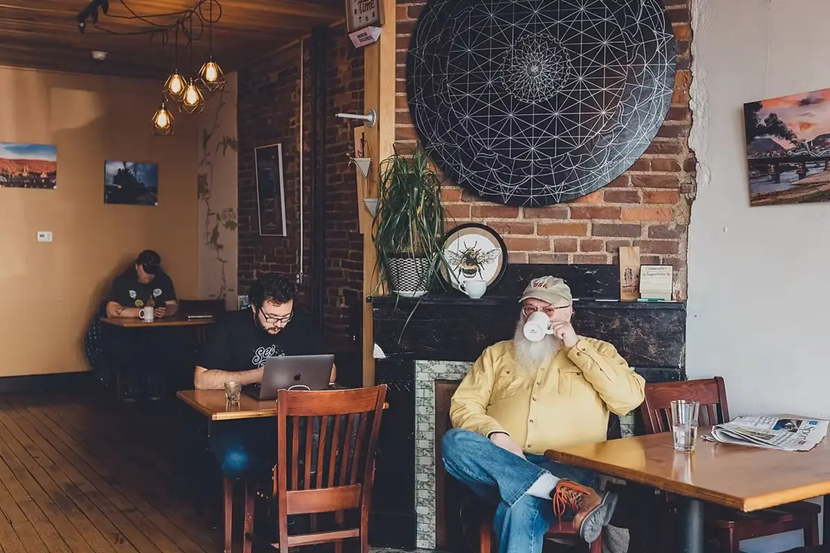 People working and a man sipping coffee at Basecamp Coffee Co.