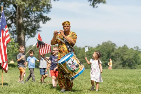 Man playing the flute and leading marching kids at Mount Vernon's Freedom Before Emancipation: Family Day for Juneteenth