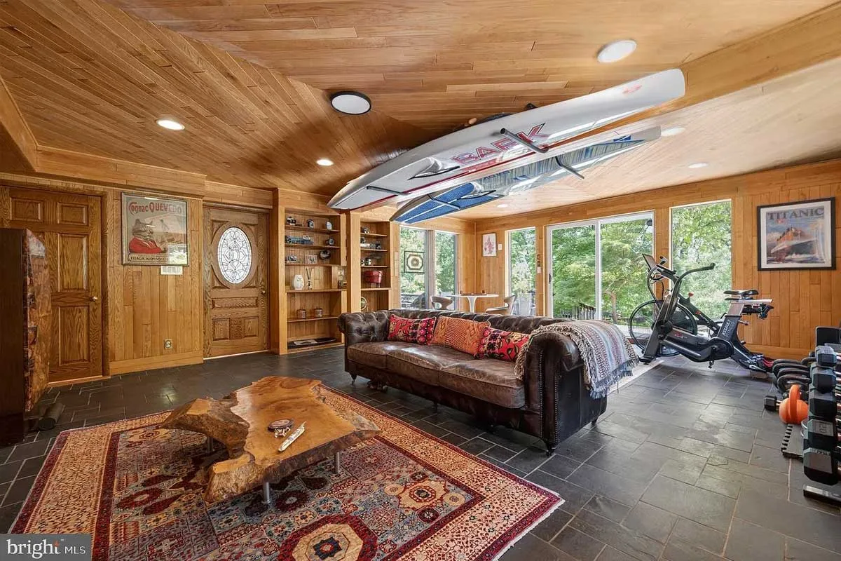 wood-covered living room with surfboard on ceiling