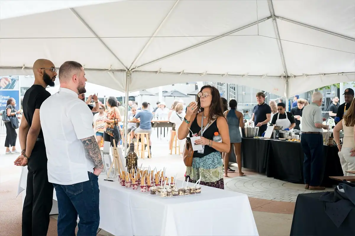 people sample food under a tent at Taste of Tysons