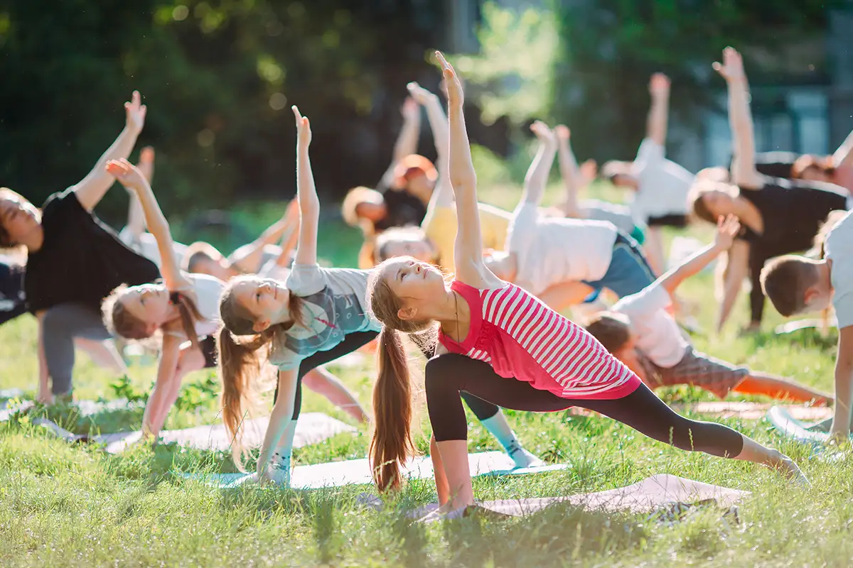 kids on mats outside in the grass in yoga poses