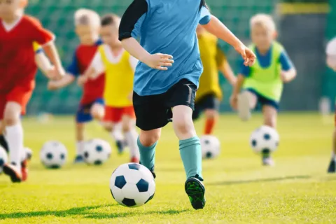 kids on a field kicking soccer balls