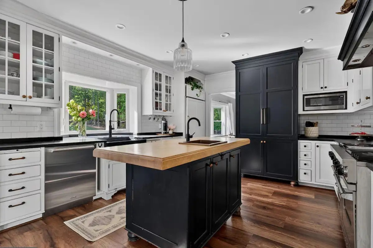 Kitchen with black paneled cabinetry, soapstone countertops, professional-grade gas range, and island of 3204 Mountain Rd