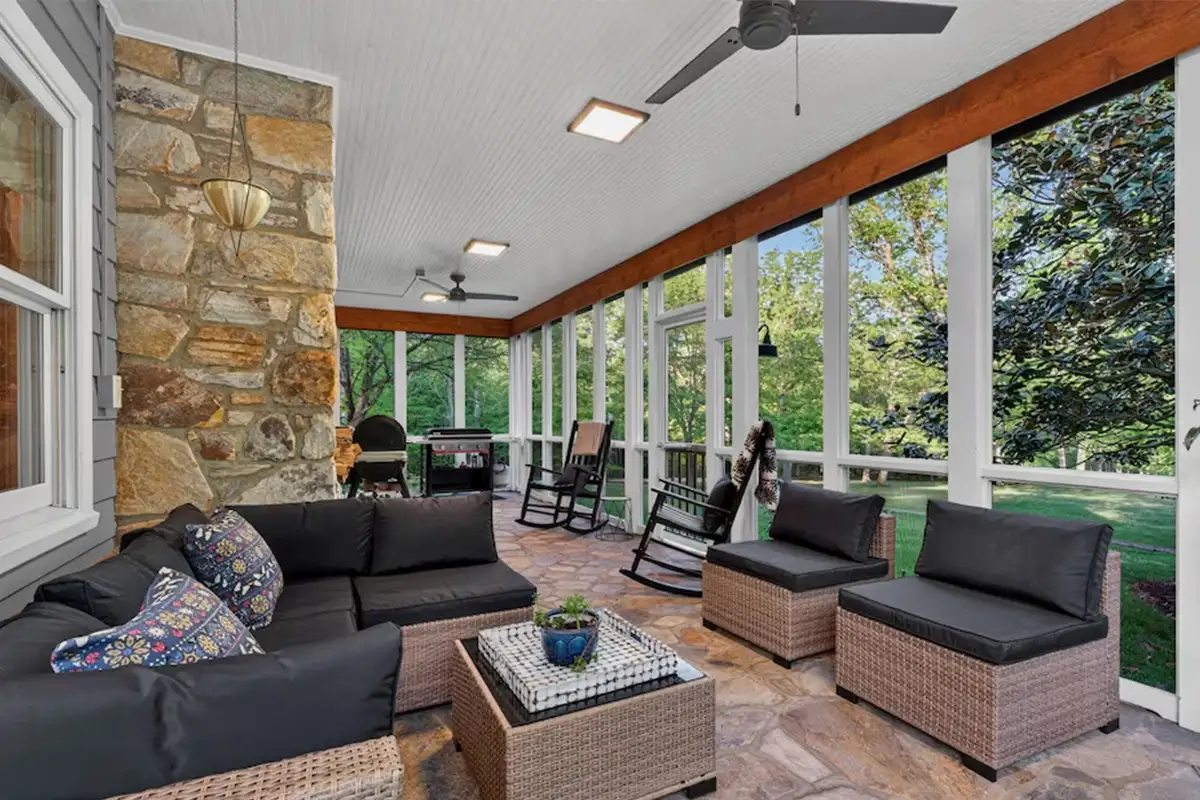 Partially enclosed wrap-around porch with stone flooring and fireplace of 3204 Mountain Rd