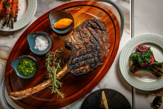 omahawk steak finished with smoked paprika sea salt, chermoula, and romesco sauce at Cielo Club