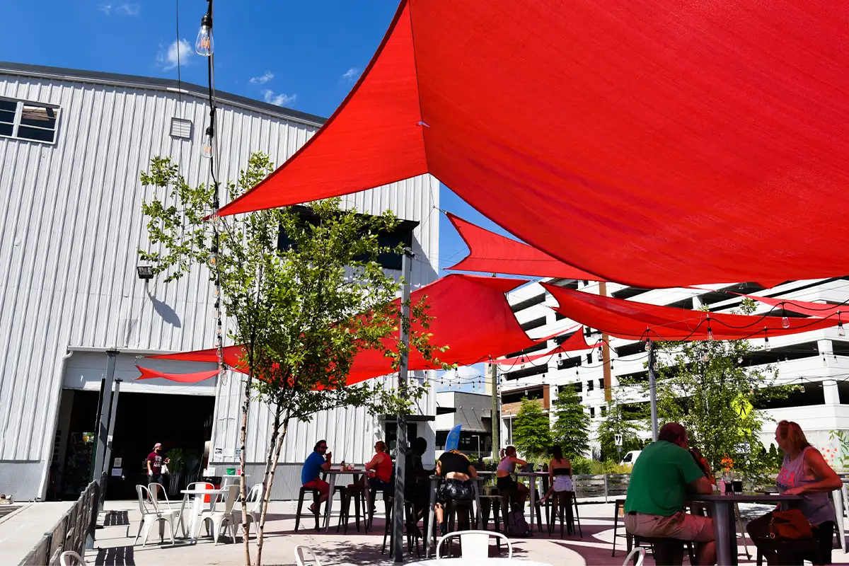people sit outside at Caboose Commons under a red awning