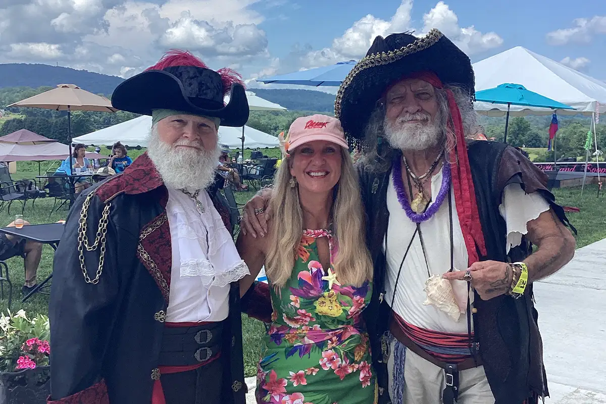 2 men dressed as pirates and a woman in a floral dress at Breaux Vineyards