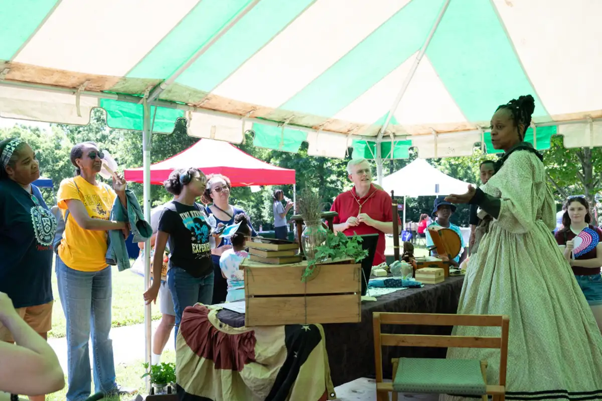 People watching Juneteenth reenactor under a tent at Sully Historic Site