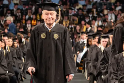 Ken Grundborg walks up the aisle at graduation in a cap and gown
