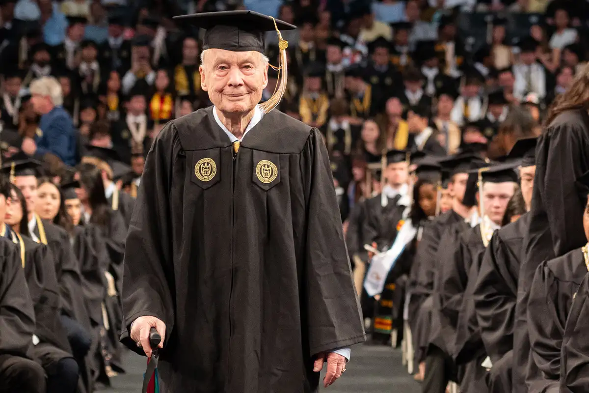 Ken Grundborg walks up the aisle at graduation in a cap and gown