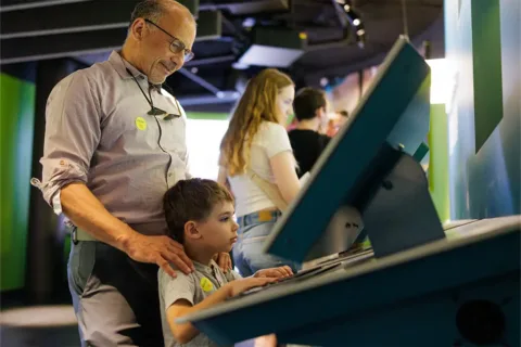 Man and child looking at exhibit screen at National Geographic Museum
