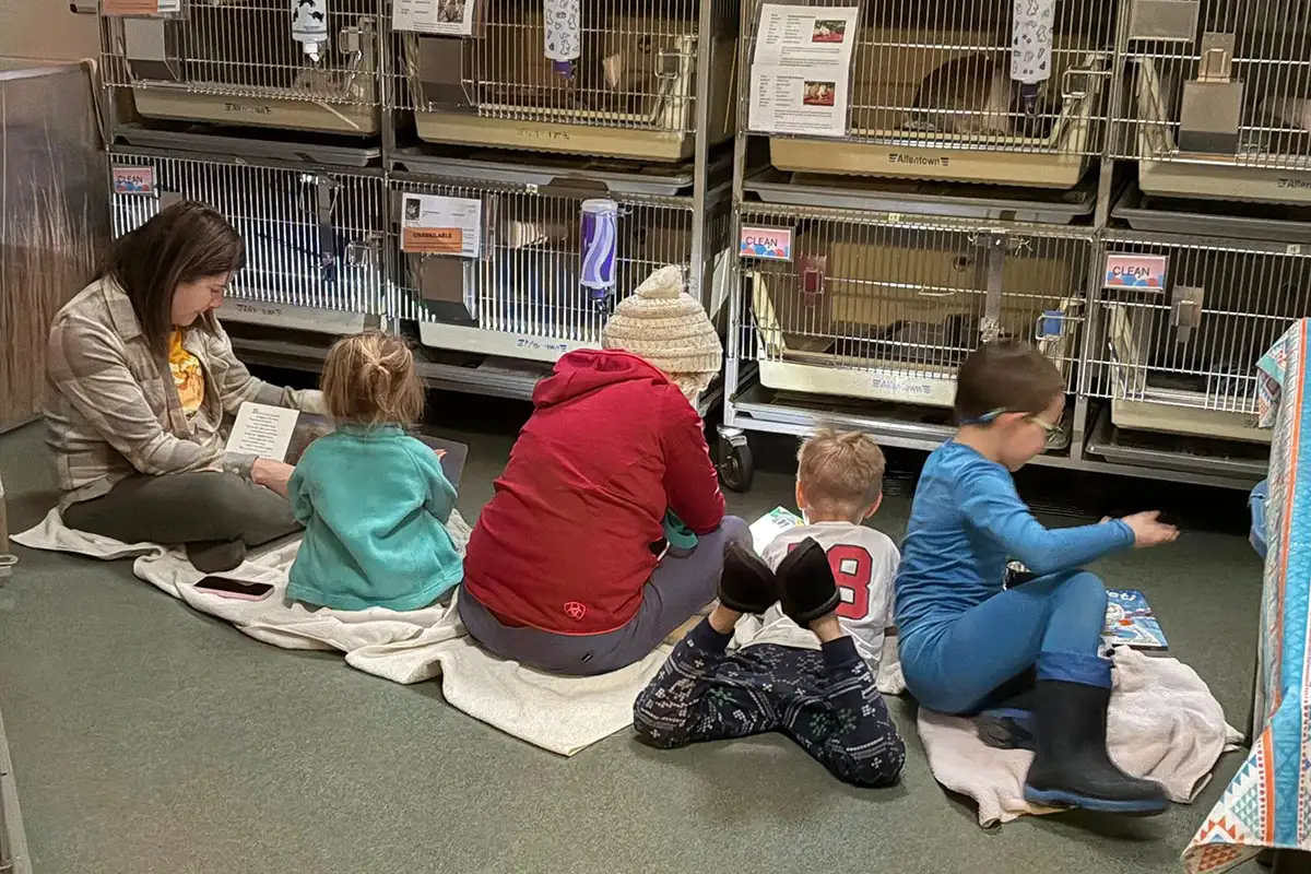children read in front of animal cages at a Fairfax County animal shelter