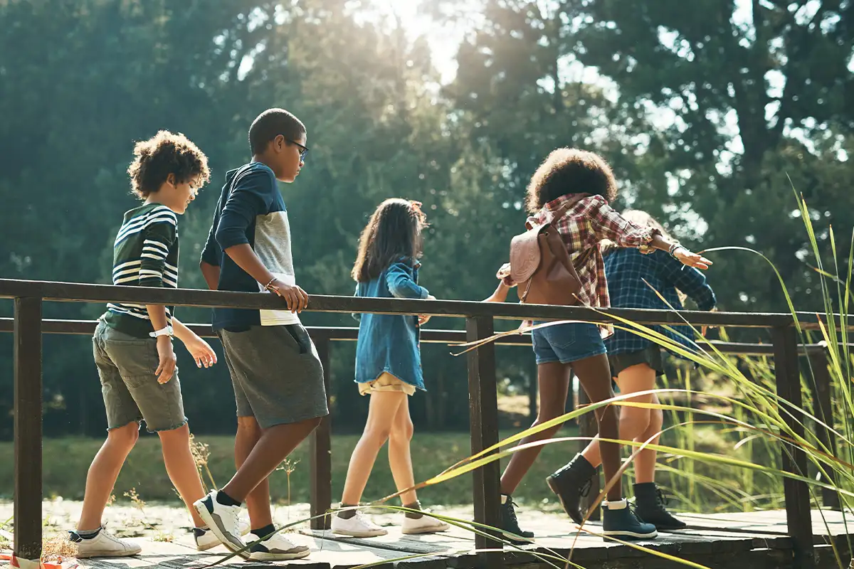 kids walk across a bridge in a park