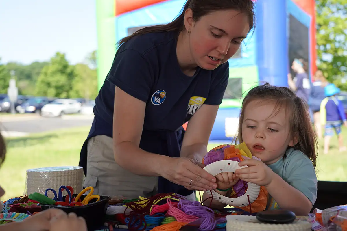 a Loudoun Parks employee helps a small girl with an art project
