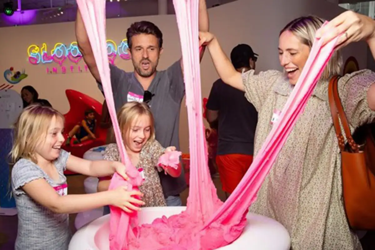 a family plays with pink slime at Sloomoo