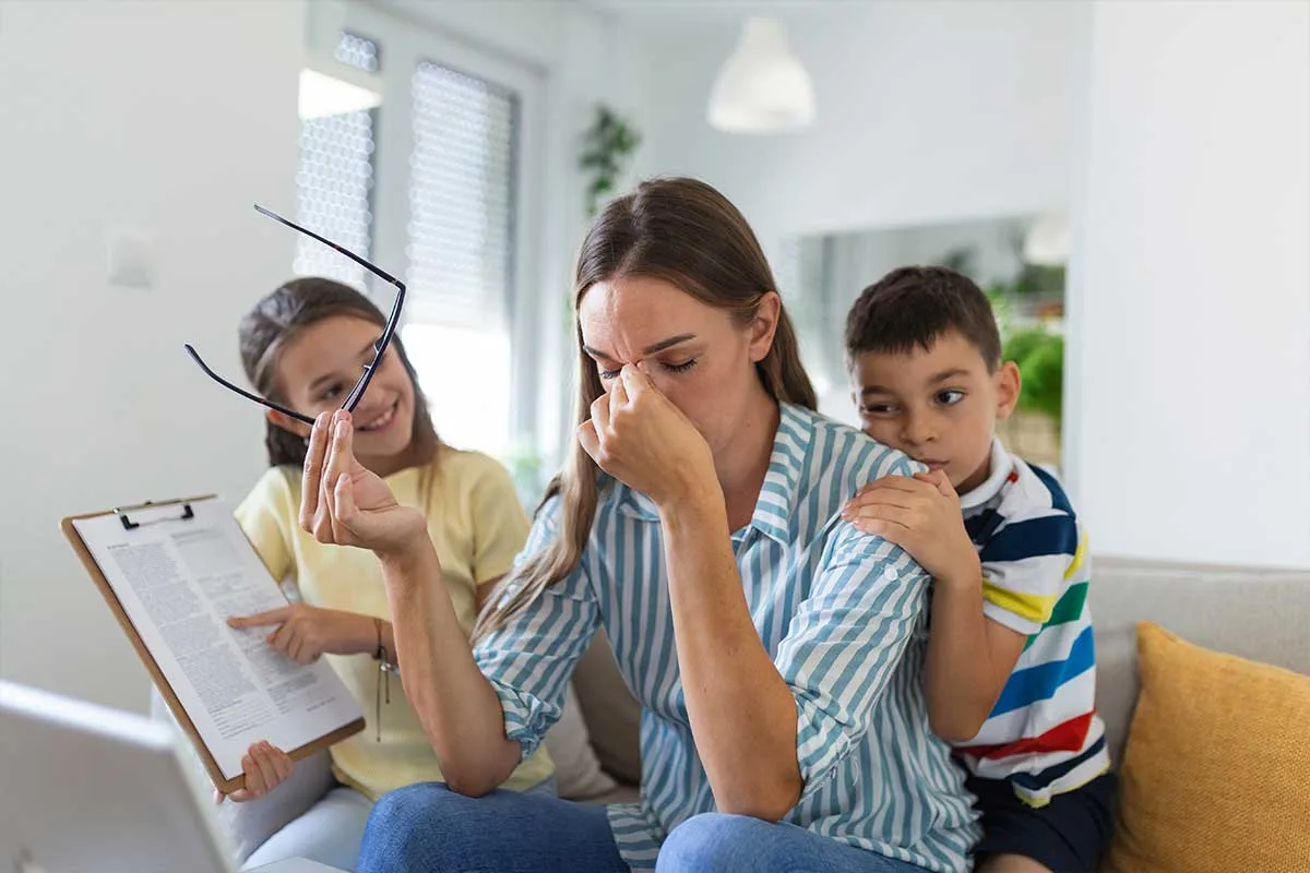 parent sitting and holding head with two kids