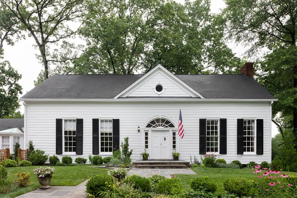 Exterior of white 1942 classic revival home in Arlington Ridge with black shutters