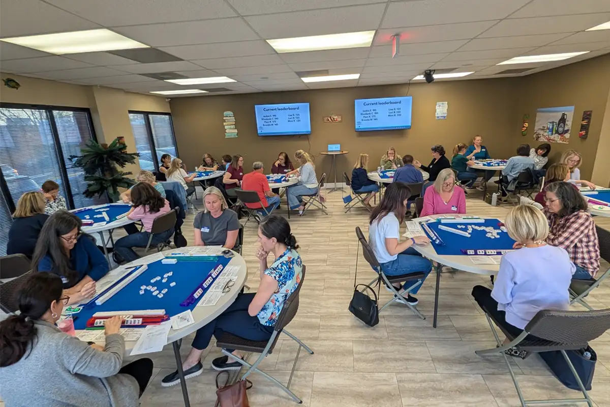 Room of women playing mahjong around tables