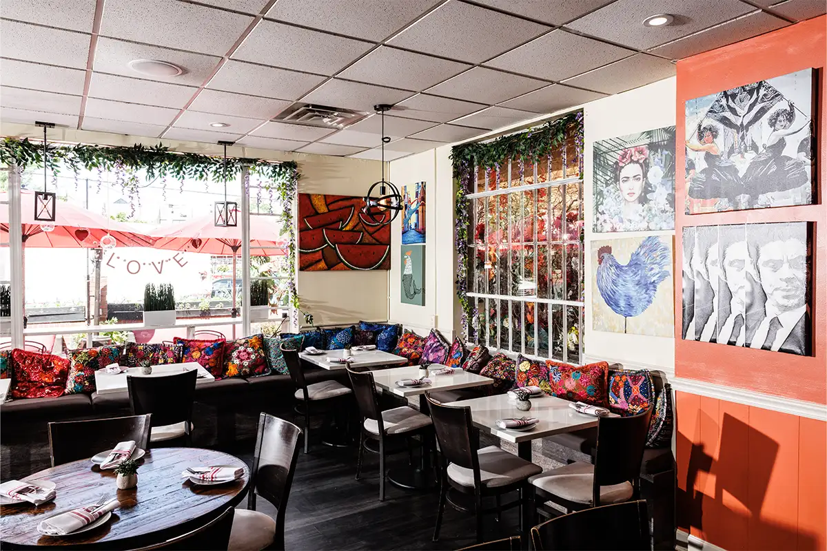 Interior of Pikoteo with artwork, orange and white walls, colorful pillows, and plant decor