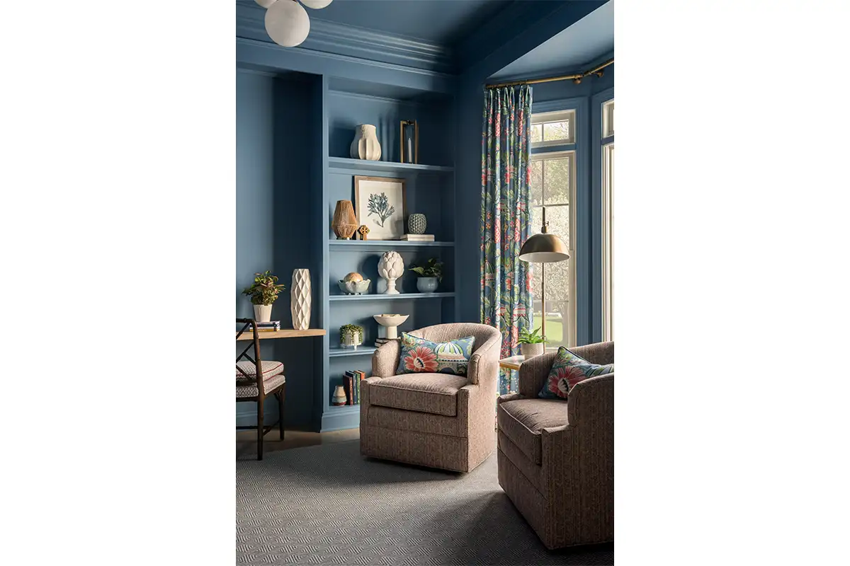 Blue redone office with built-in shelves, patterned rug, curtain, and chairs